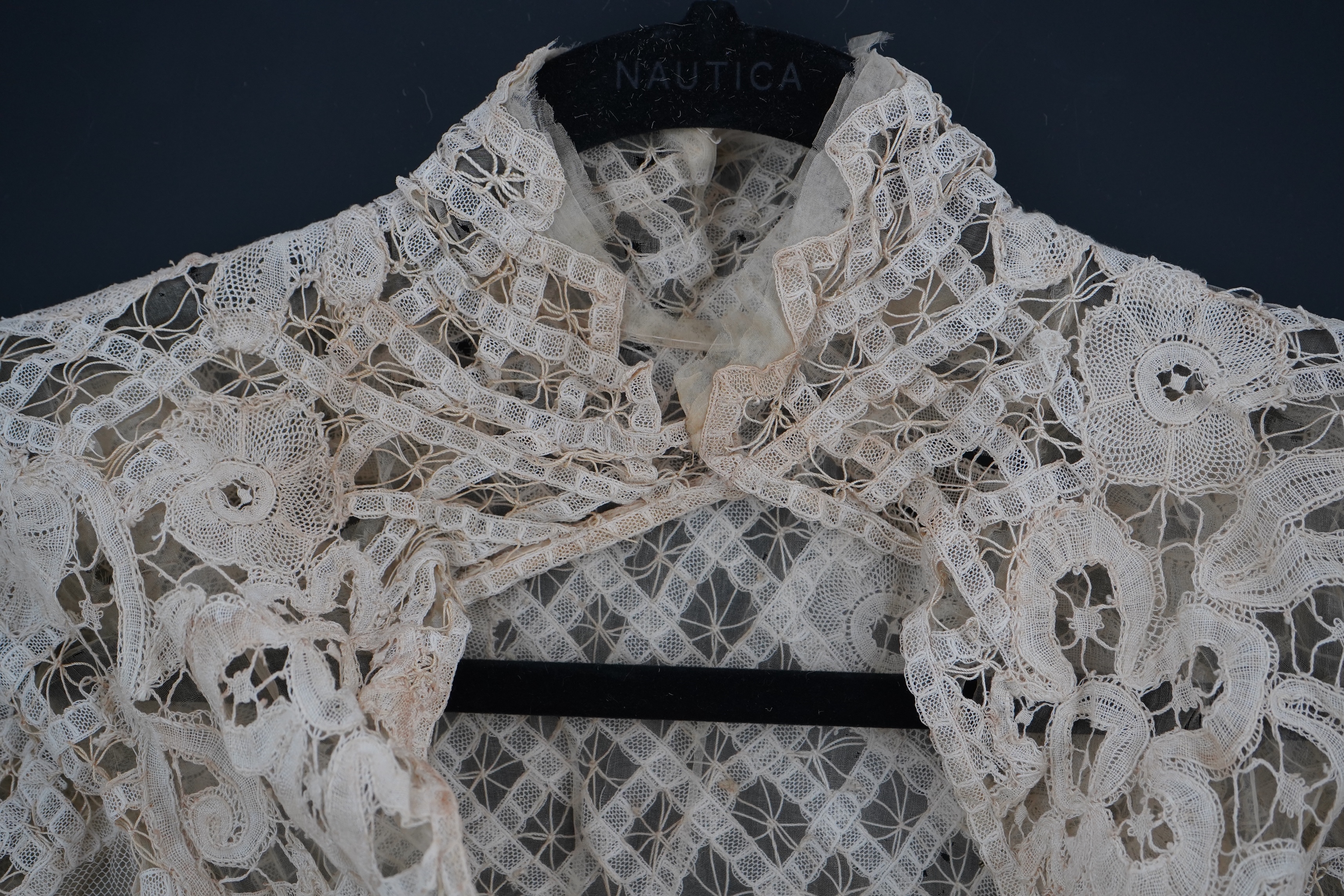 An Edwardian high collared cream tape lace wedding over blouse, made with a deep net frill and cream chiffon rose detail hanging from lower edge, top of collar to rose detail at the front 46cm. Condition - fine silk chif